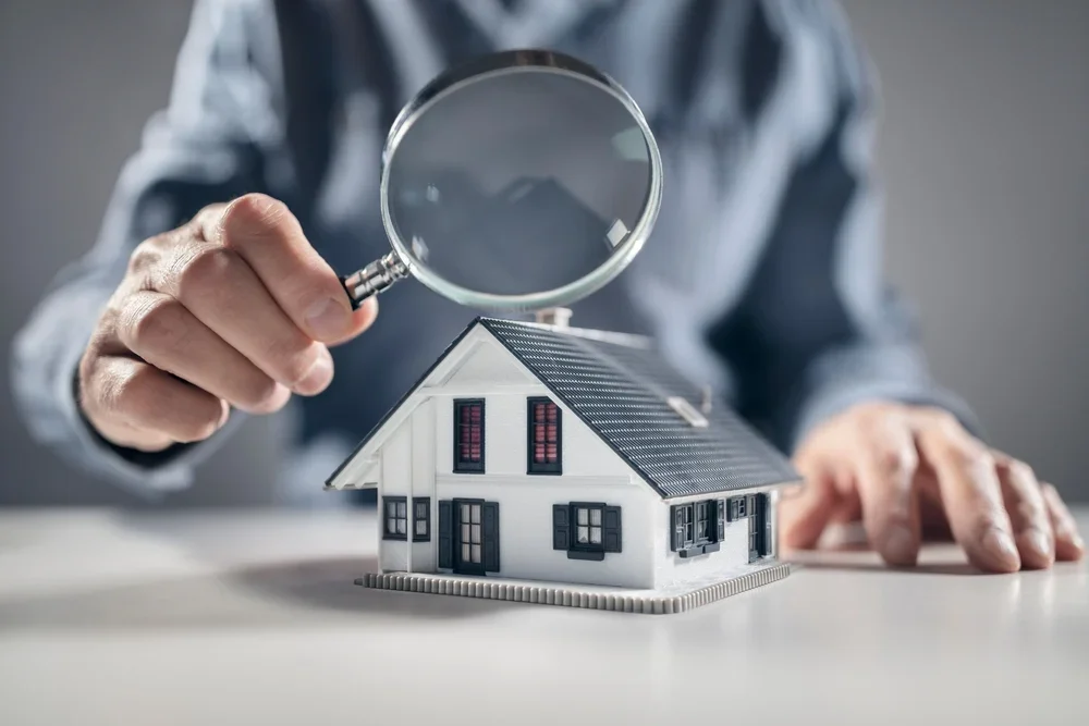 Estimation maison canton de Vaud – expert immobilier avec loupe analysant une maquette de maison